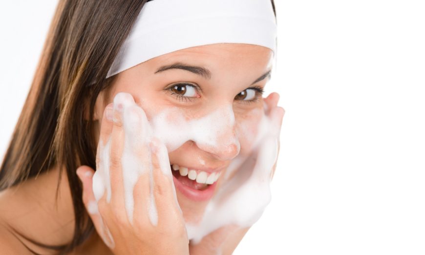 woman washes face with cleansing foam