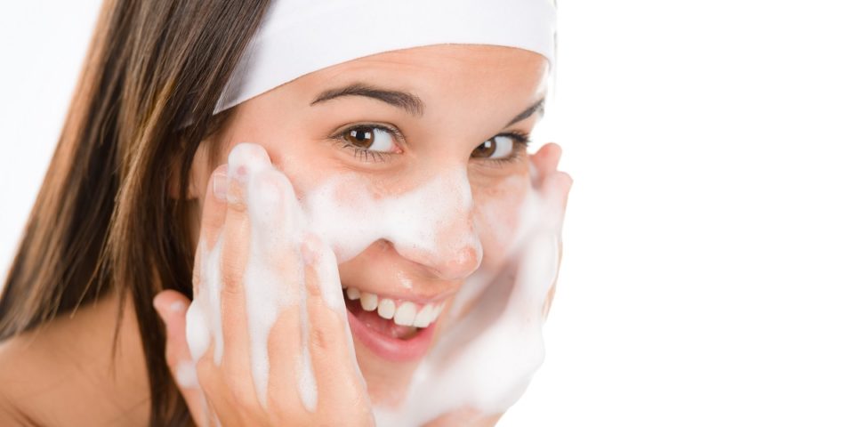 woman washes face with cleansing foam